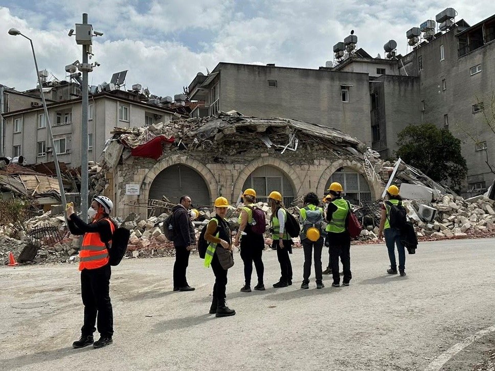Photo of a team of experts in the middle of a street with buildings heavily damaged by earthquake